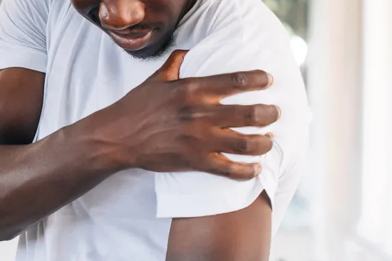 photo of man rubbing sore shoulder