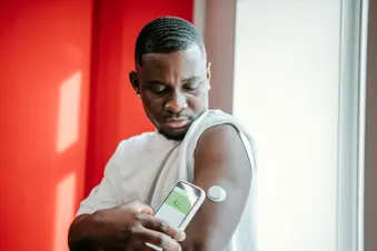 photo of man checking blood glucose with wearable sensor