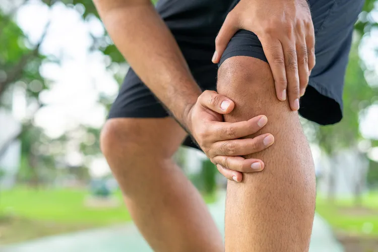 photo of man holding sore knee