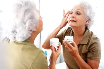 elderly woman putting lotion on face