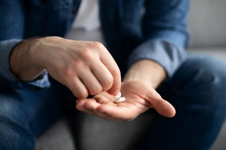 photo of man taking pills from the palm of his hand
