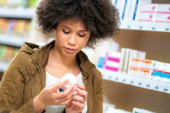 photo of woman reading pill bottle label