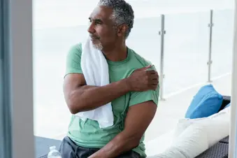 photo of man holding shoulder in slight pain