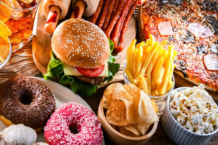 Close up of junk food including burgers, donuts and chips 