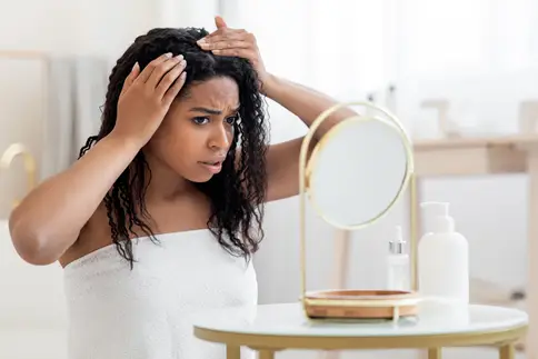 photo of Woman in mirror looking at her hair line