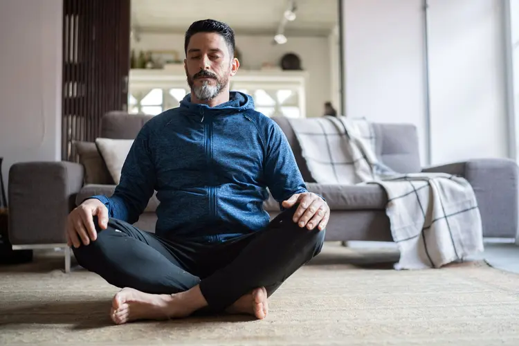 photo of mature man meditating in living room