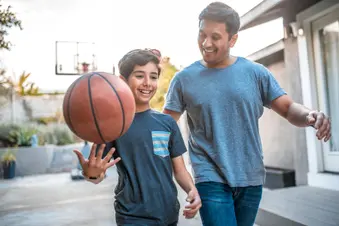 photo of father and son playing basketball