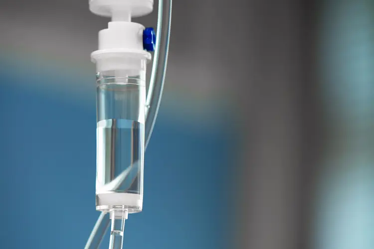 A close-up photo of an IV tube with a dropper with the drug slowly dripping down tube.