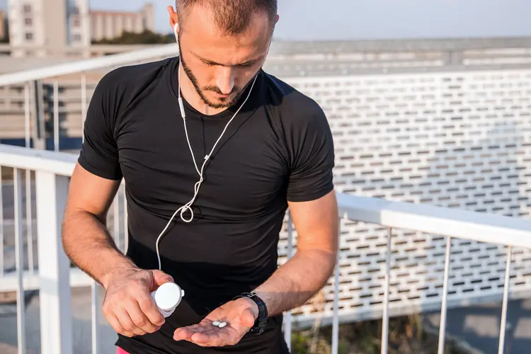 photo of young man taking supplements outdoors