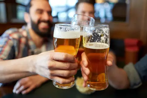 photo of three men at happy hour cheering each oth