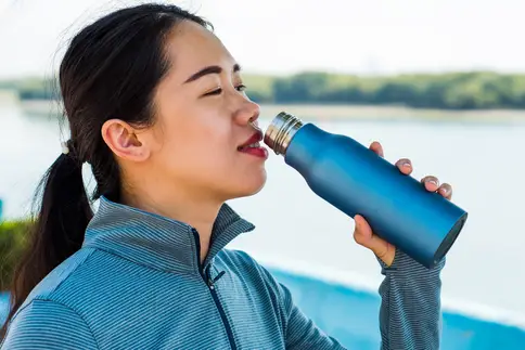 photo of woman drinking from water bottle