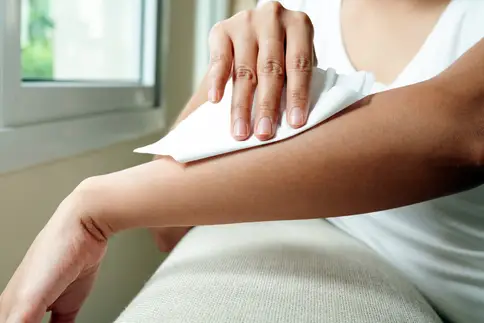 photo of woman wiping arm with tissue