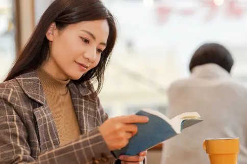 photo of woman reading book in cafe