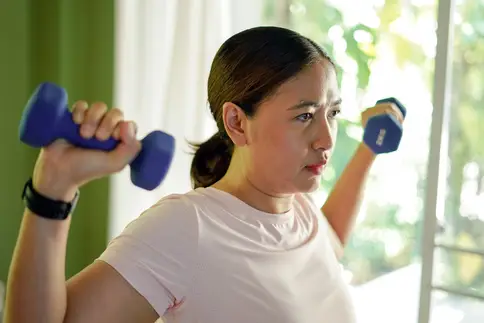 photo of woman exercising with hand weights at home