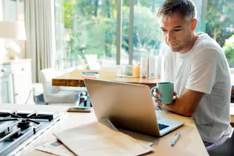 photo of mature man working at home and drinking morning coffee
