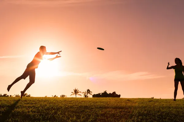 photo of couple playing frisbee