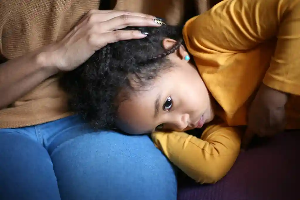photo of child laying in mother's lap
