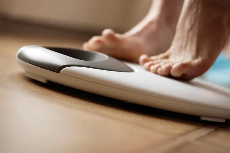 photo of woman stepping onto weight scale