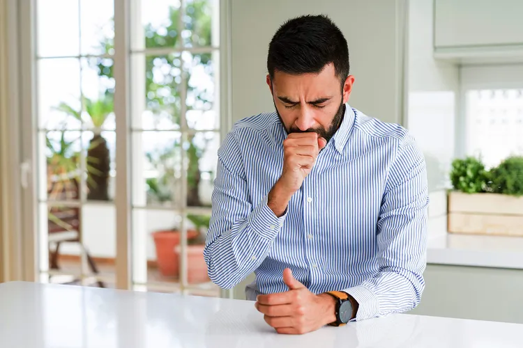 photo of man coughing in kitchen
