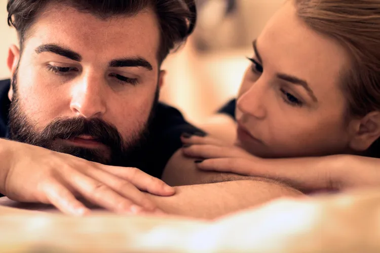 photo of man and woman talking on bed