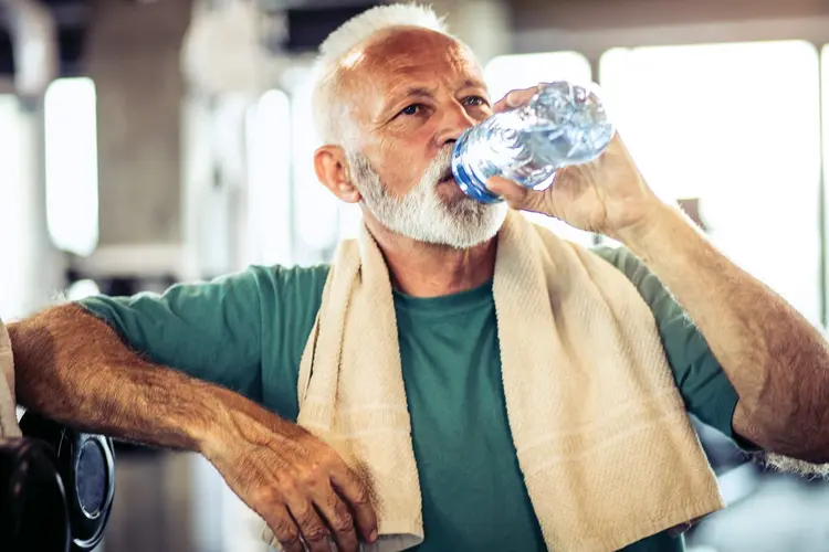 senior man drinking water in gym