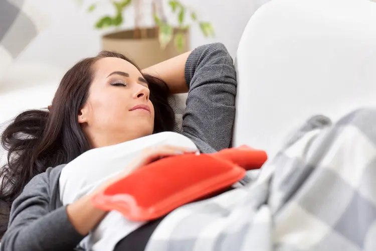 photo of woman on sofa using hot water bottle