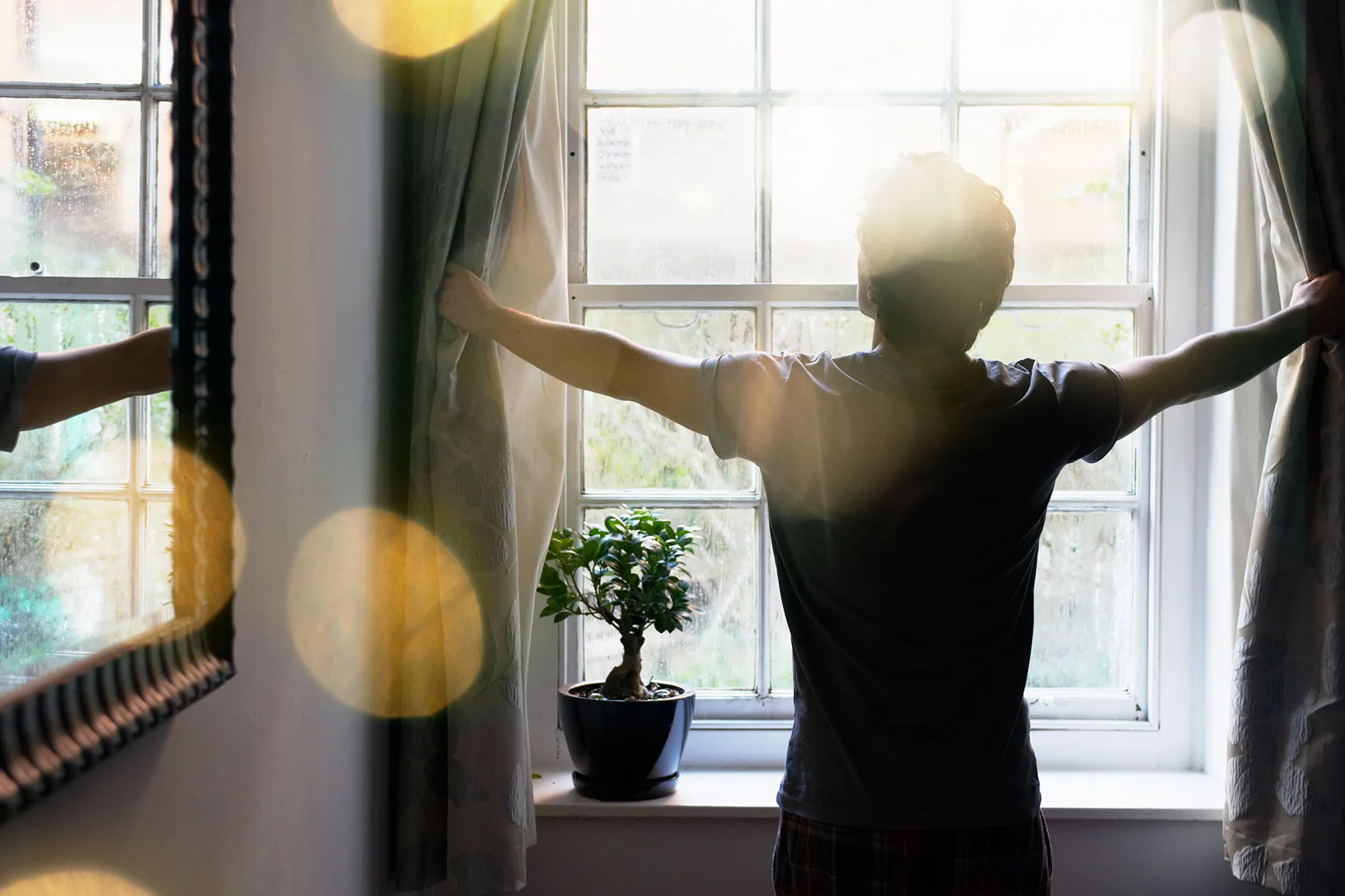 photo of man opening curtains
