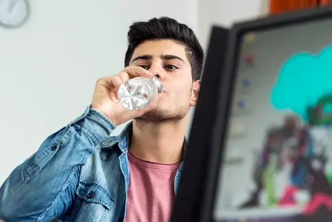photo of young man drinking bottled water