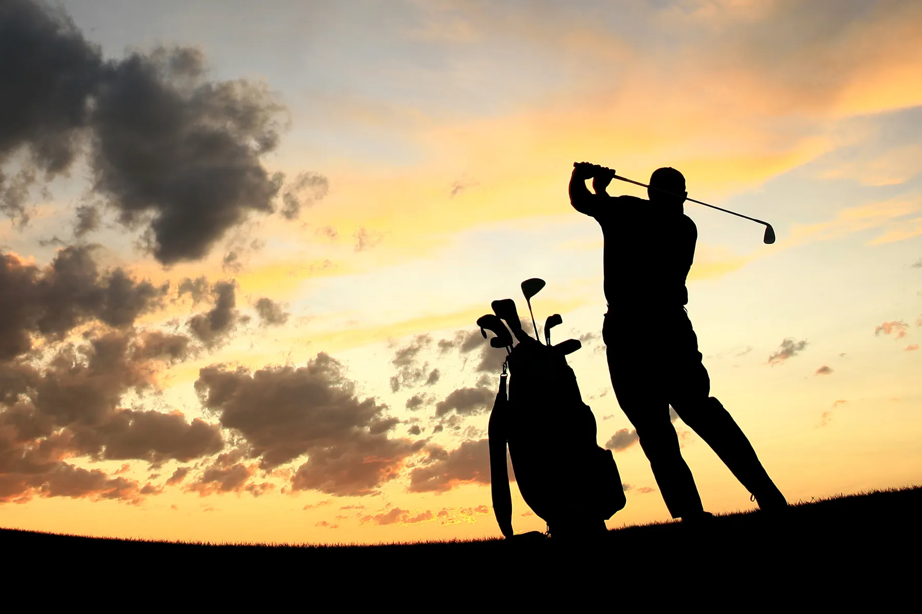 photo of man playing golf at sunset