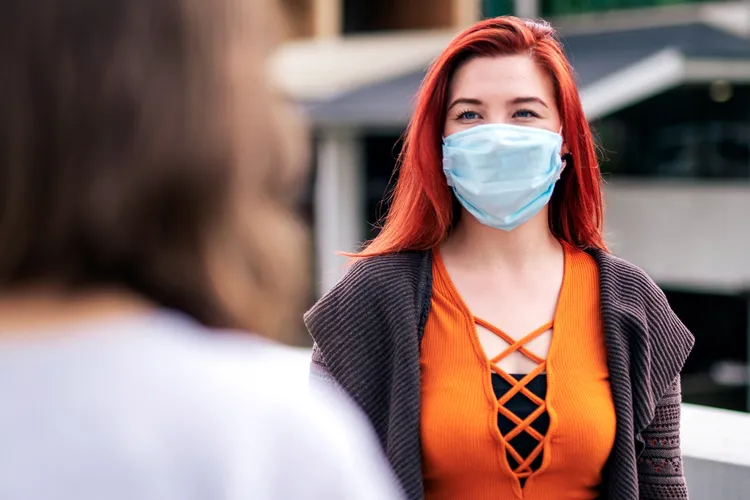 photo of woman talking while wearing a mask