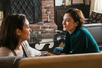 photo of adult sisters having discussion on sofa at home