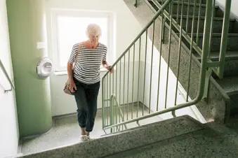 photo of senior woman walking up stairs in apartment building
