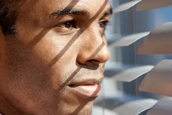man looking through blinds