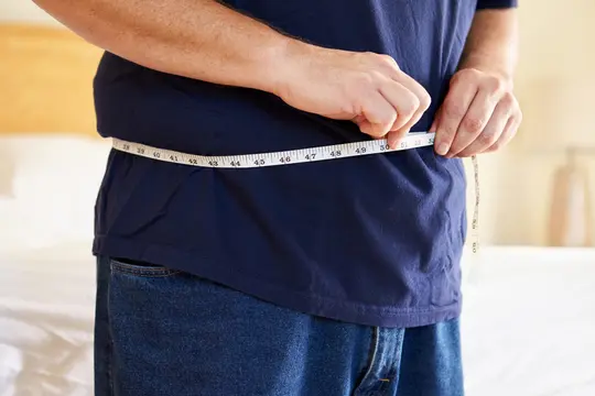photo of man measuring waistline