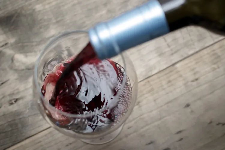 photo of red wine pouring from bottle in glass