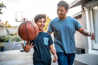 photo of father and son playing basketball