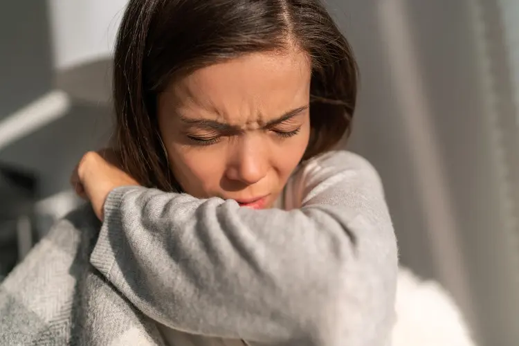 photo of woman sneezing into arm