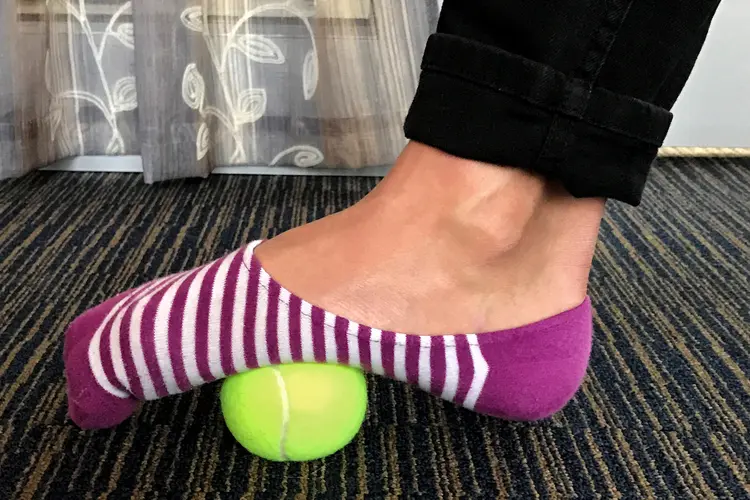 photo of man with foot on tennis ball