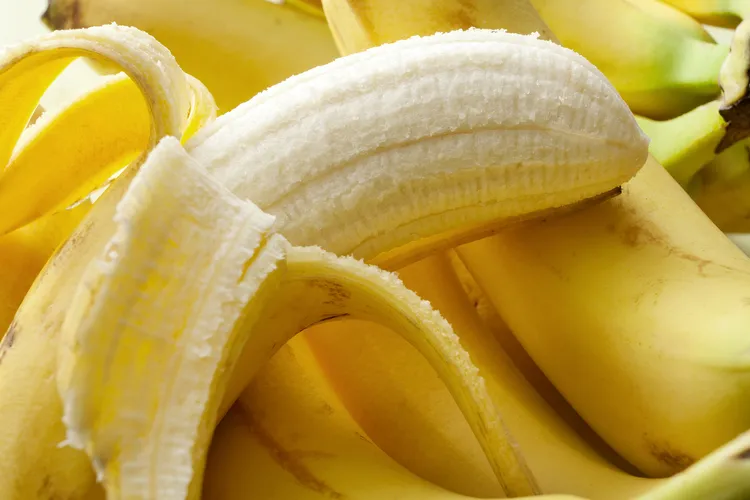 photo of peeled banana on top of bananas