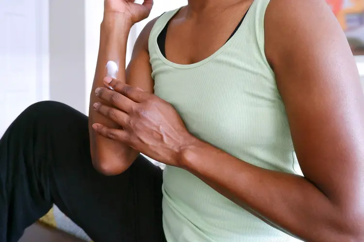 photo of woman massaging cream into arm