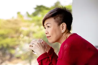 photo of mature woman enjoying coffee break on balcony,